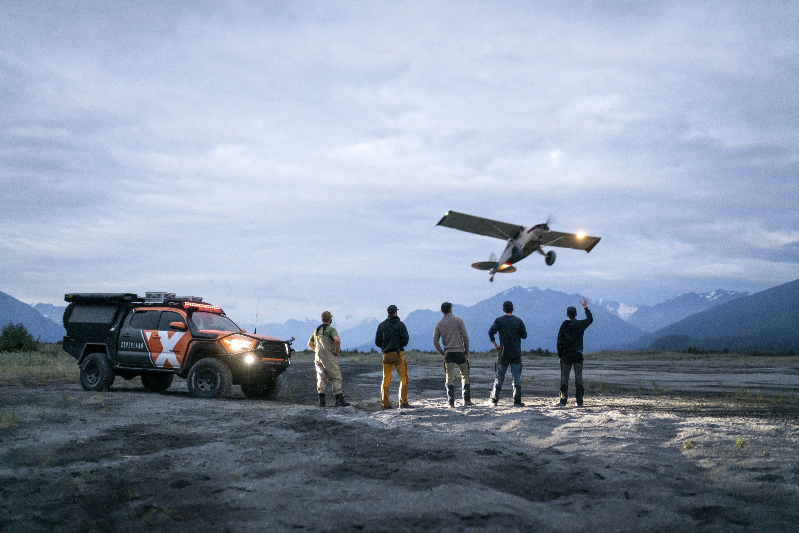 shows a team of overlanders with a Toyota tacoma and a low-flying plane