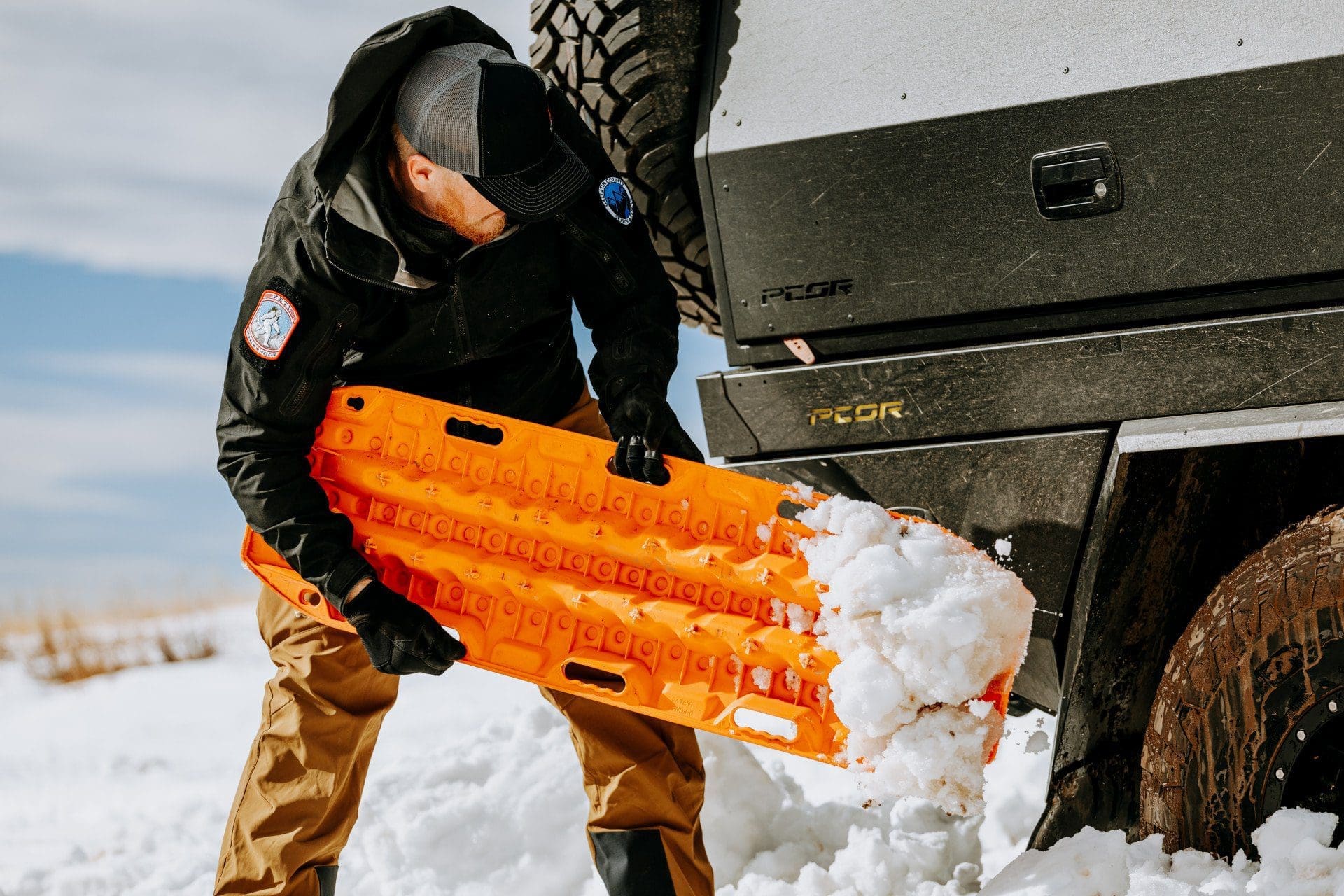 Person placing Maxtrax® under truck wheel in heavy snow